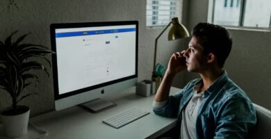 man in blue denim jacket facing turned on monitor